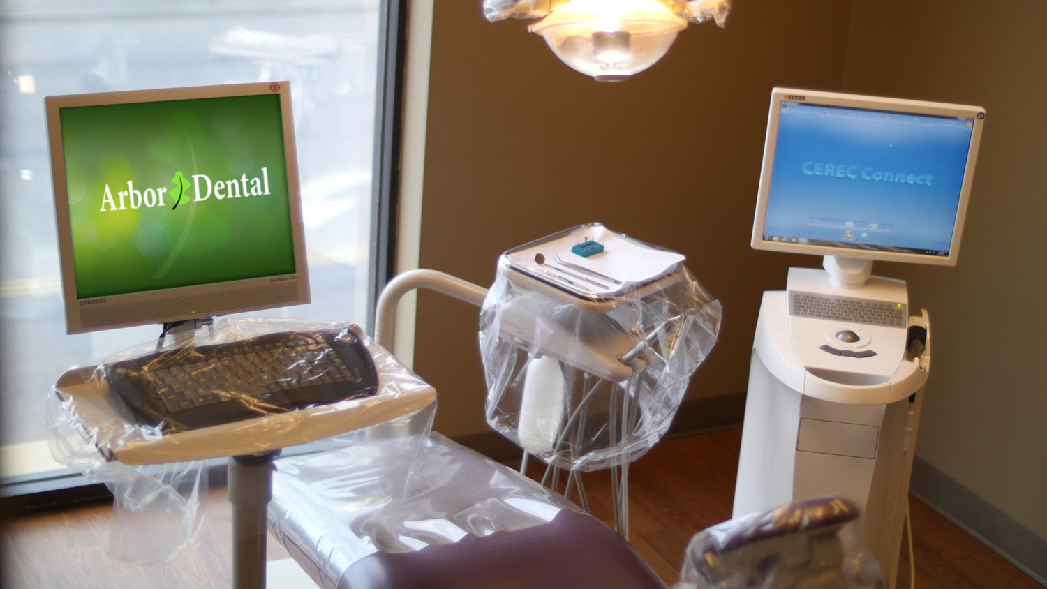 The image features a dental office setup with a computer monitor displaying an advertisement for Abort Dental alongside a chair, a desk with a keyboard, and a computer mouse, all within a room that appears to be in a dental practice, as indicated by the presence of a dental chair, a monitor showing dental images, and a sign indicating a dental office.