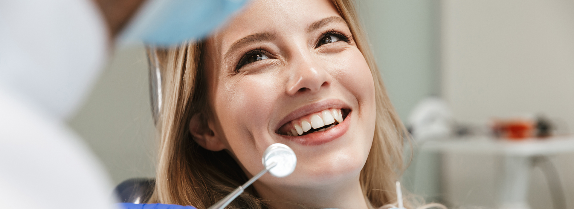 A smiling woman receiving dental care from a dentist.