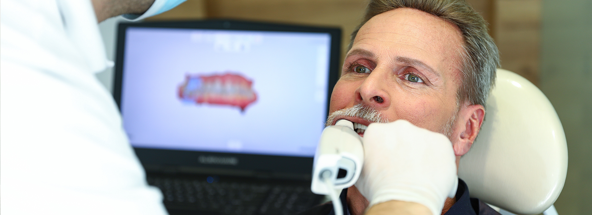 A man receiving dental care with a dentist adjusting his mouthpiece.