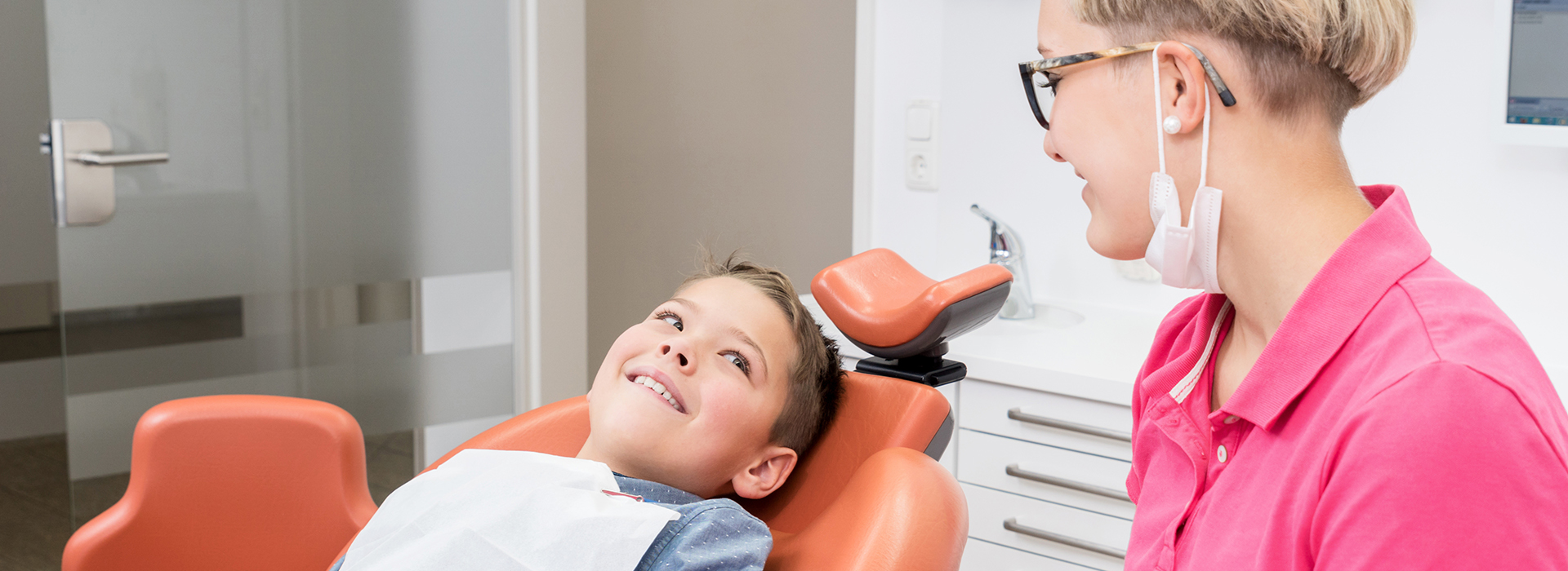 An image featuring a dental professional assisting a young child during a dental examination.