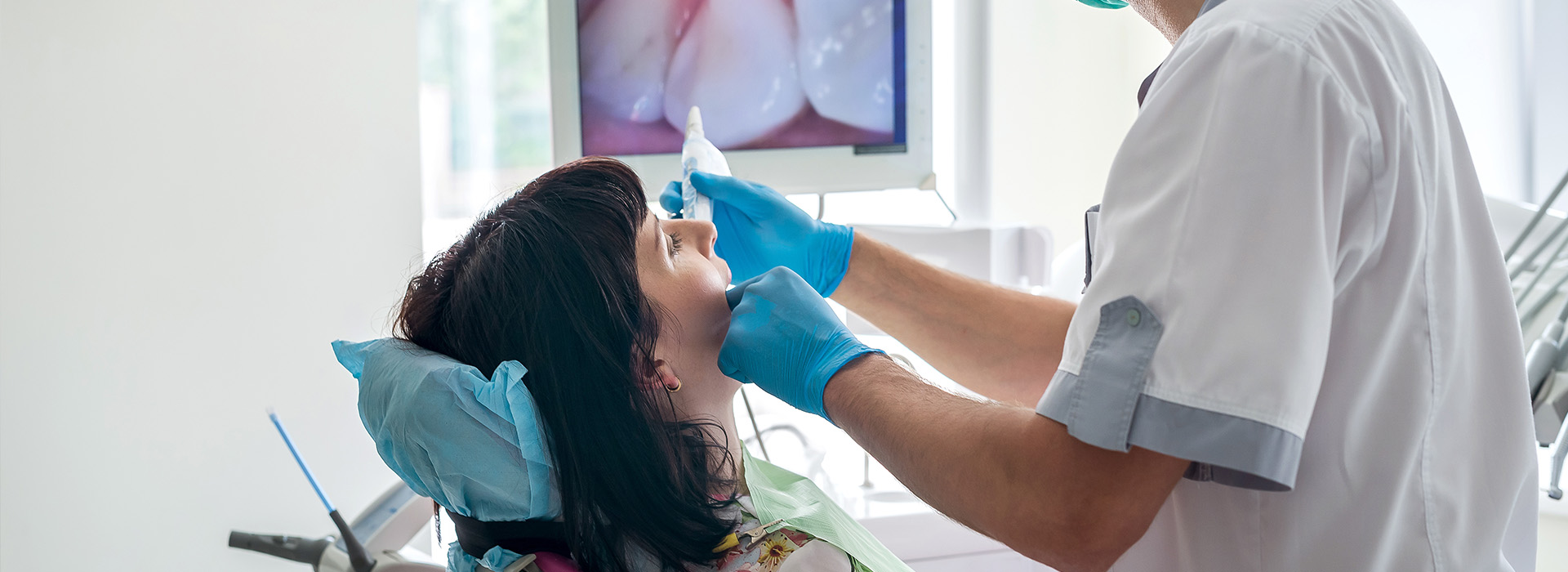 A dental hygienist performing oral care procedures on a patient in a dental office setting.