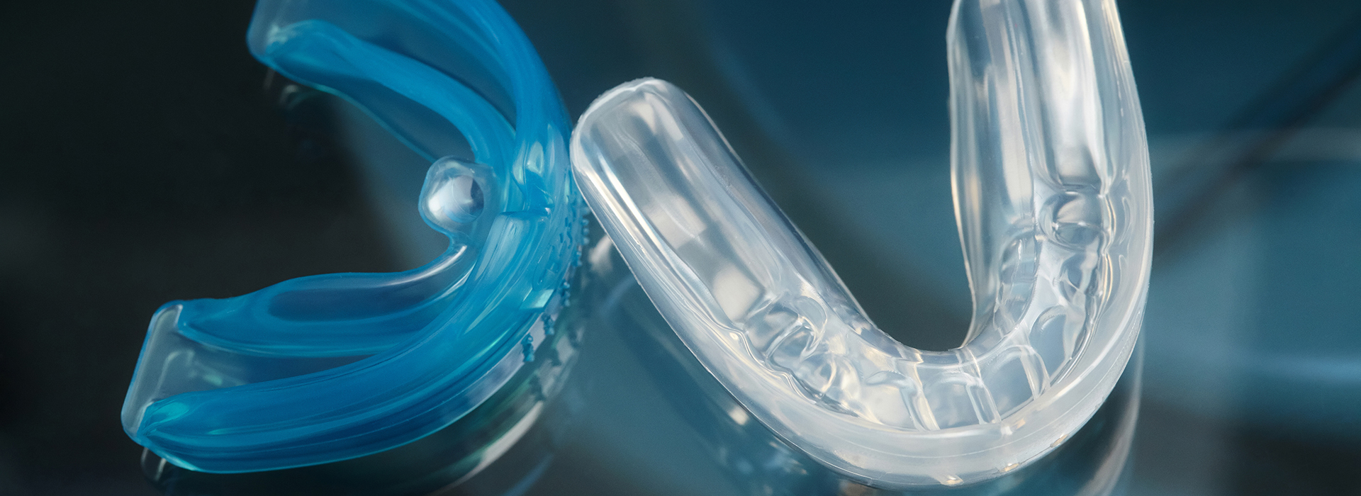 The image displays a clear plastic dental retainer with a blue toothbrush handle partially inserted into its center.