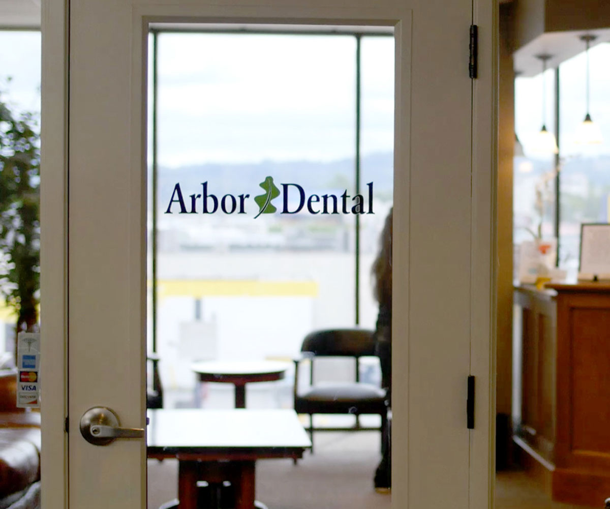 An interior view of a dental office entrance with an Arbor Dental sign above the door.